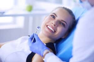 Woman with porcelain veneers smiling in a dentist's chair