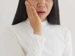 Woman with an old filling holding her jaw