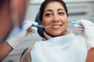 Woman sitting in a dentist's chair and smiling while getting a dental crown or veneer
