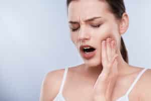Woman who needs a root canal holding her jaw